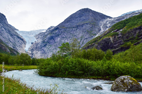 Waterfall, river and Briksdalsbreen (Briksdal) glacier. The melting of this glacier forms waterfall and river with clear water. Jostedalsbreenen National Park. Norway. photo
