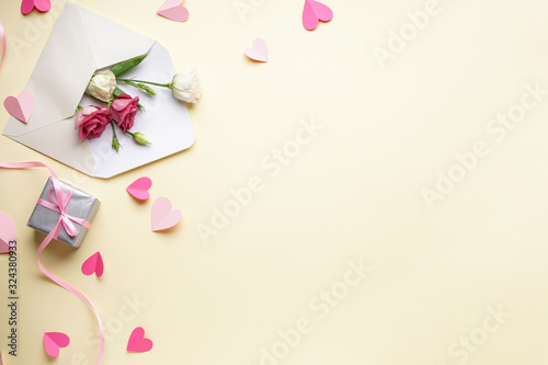 Beautiful eustoma flowers in an envelope, a gift box and confetti on a yellow background, a place for a text, flat lay. 8 March, International Women's Day. © VI Studio