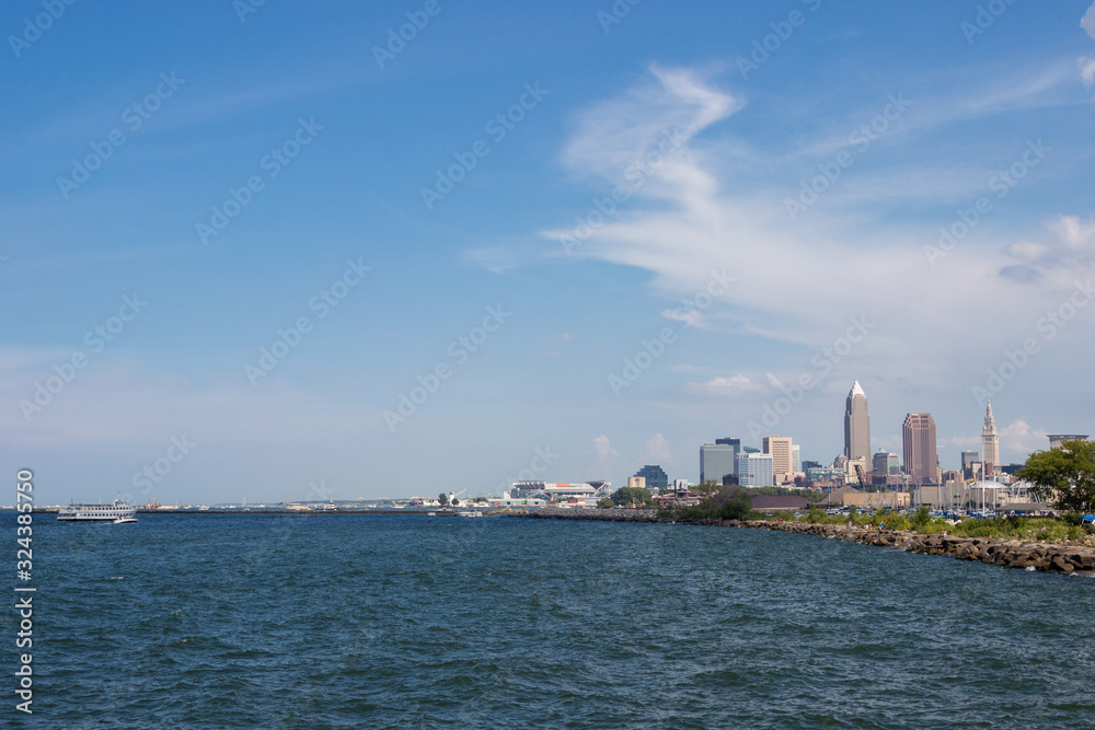 Beautiful summer landscape, which depicts the rocky shore of the lake, waves on the water and in the distance are the pain of skyscrapers. View of city of Cleveland,Ohio,USA from the lake Erie