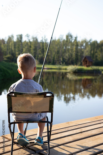 background. a boy with a fishing rod sits in a chair and catches a fish