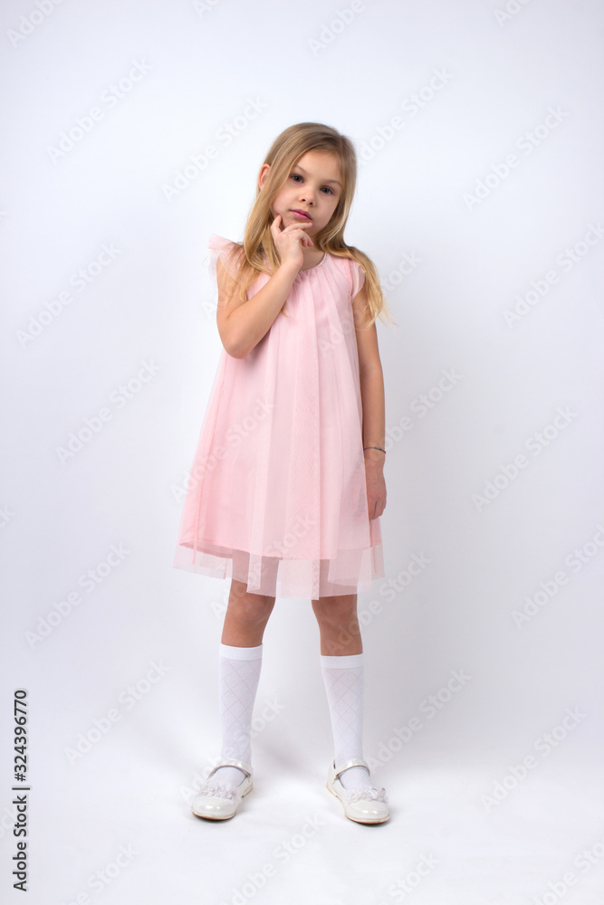 little blonde girl of six seven years with long hair in a light pale pink dress, white golf and white shoes on a white background little blonde girl of six seven years with long hair in a light pale pink dress, white golf and white shoes on a white background