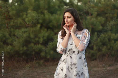Woman dressed in a beautiful light dress with floral print on the nature.