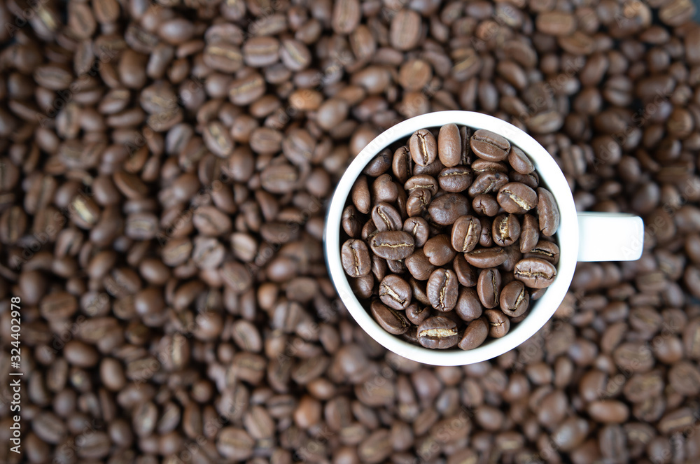 background. defocusing. Coffee beans in a white cup and on the table. background. defocusing. Coffee beans in a white cup and on the table.