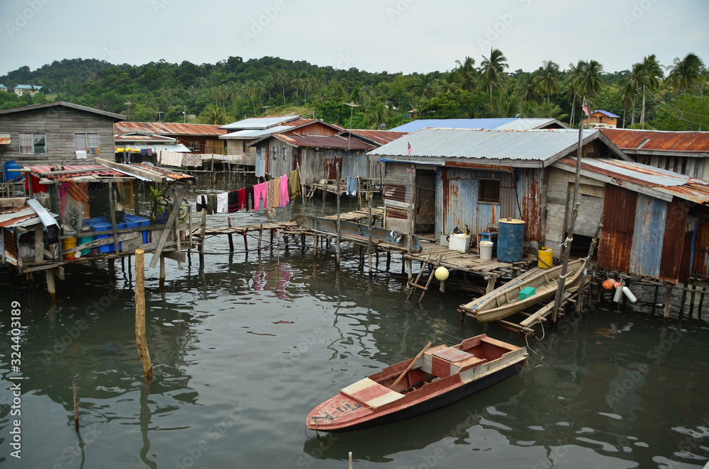 Stilt houses and cabins in a floating village scene with laundries drying on a washing line and small boats moored beside a boardwalk on Borneo river Stilt houses and cabins in a floating village scene with laundries drying on a washing line and small boats moored beside a boardwalk on Borneo river