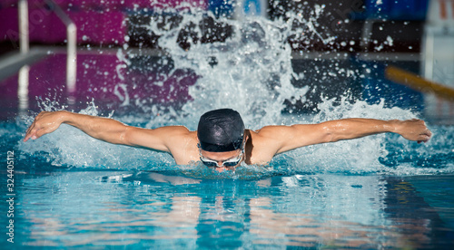 Swimmer in a cap swimming in a pool freestyle butterfly
