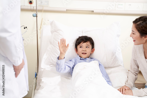 five year old asian kid waving good-bye to doctor