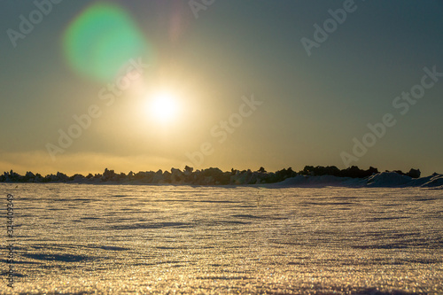 arctic lifeless landscape with hummocks on the horizon, low sun casts lens flare