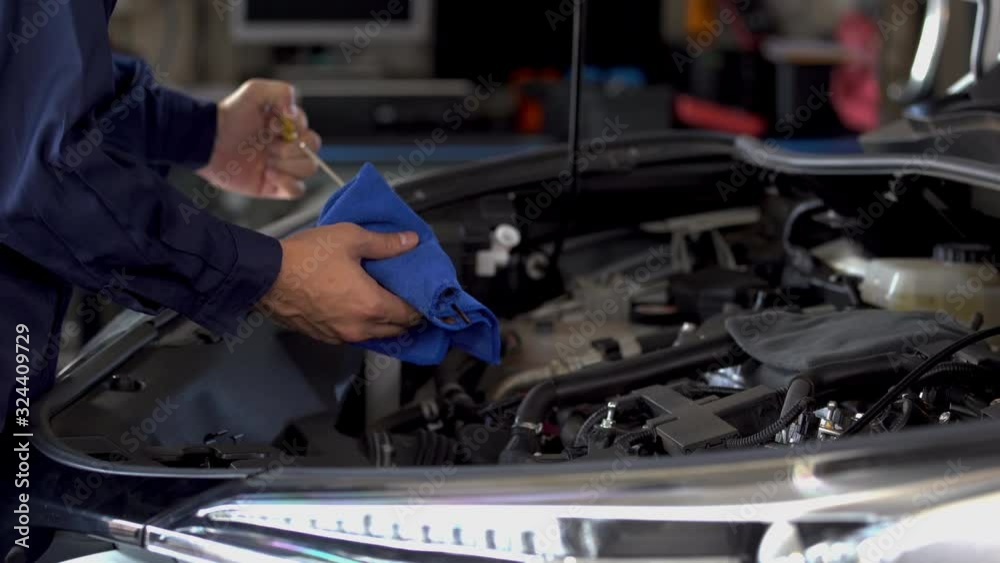 hand of technician checking the oil level on dipstick in a car engine hand of technician checking the oil level on dipstick in a car engine