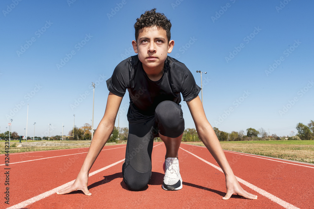 Young track athlete kneeling on his mark