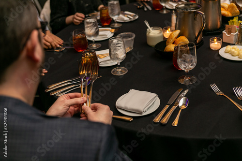 Hands holding three forks at a dinner table. photo