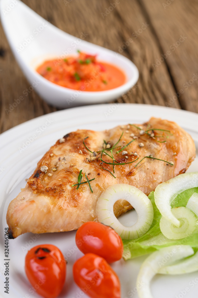 Grilled chicken on a white plate with tomatoes, salad, onion and chili sauce. Grilled chicken on a white plate with tomatoes, salad, onion and chili sauce.