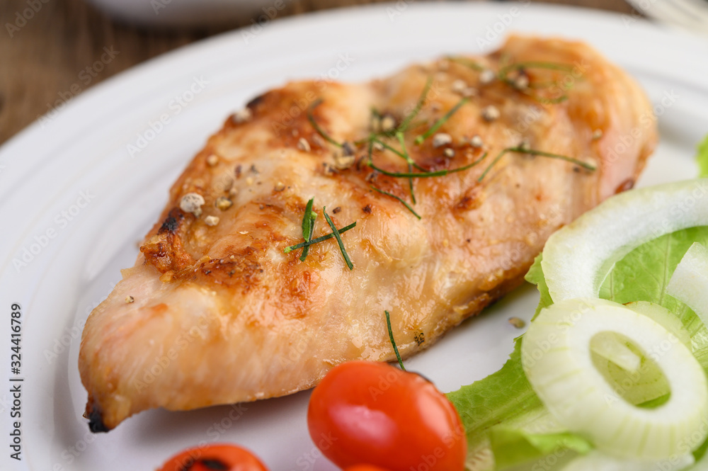 Grilled chicken on a white plate with tomatoes, salad and onion. Grilled chicken on a white plate with tomatoes, salad and onion.