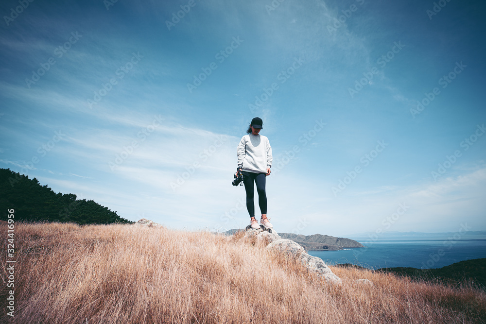 Woman photographer hiking on Makara beach, Wellington, NZ Woman photographer hiking on Makara beach, Wellington, NZ