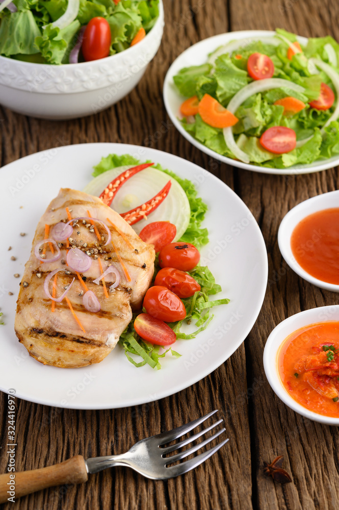 Grilled chicken on a white plate with tomatoes, salad, onion, chili and sauce.