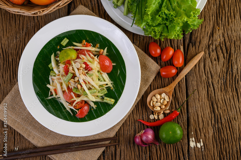 Papaya Salad (Som tum Thai) on a white plate on a wooden table.