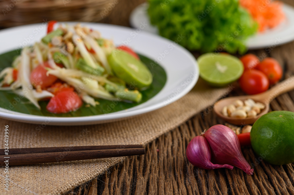 Thai style spicy food, Som Tum food concept, props decoration Garlic, lemon, peanuts, tomatoes, and shallots on wood table Thai style spicy food, Som Tum food concept, props decoration Garlic, lemon, peanuts, tomatoes, and shallots on wood table