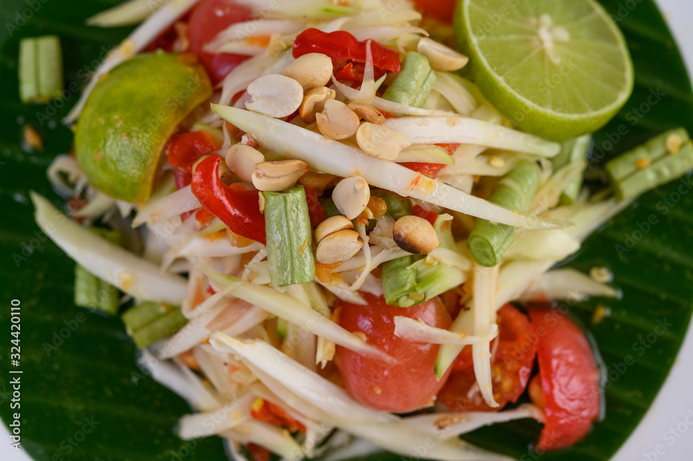 Papaya Salad (Som tum Thai) on a white plate on a wooden table. Papaya Salad (Som tum Thai) on a white plate on a wooden table.