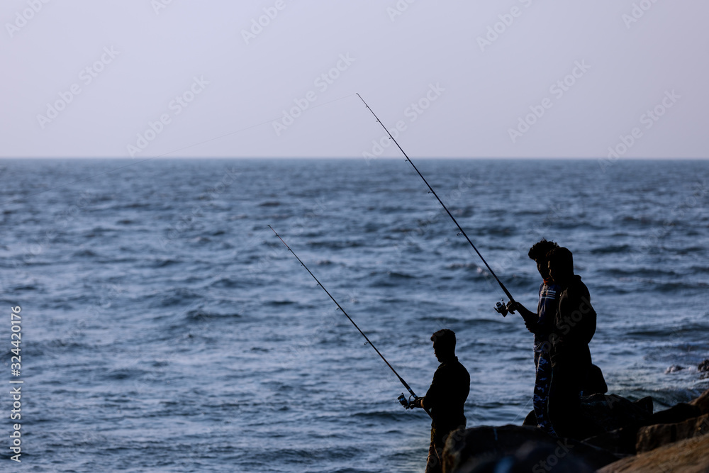 A group fo young men hopefull cast their fishing lines in the coastal waters off Kerala, India