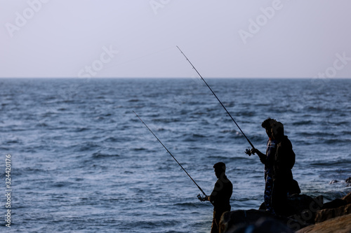 A group fo young men hopefull cast their fishing lines in the coastal waters off Kerala, India