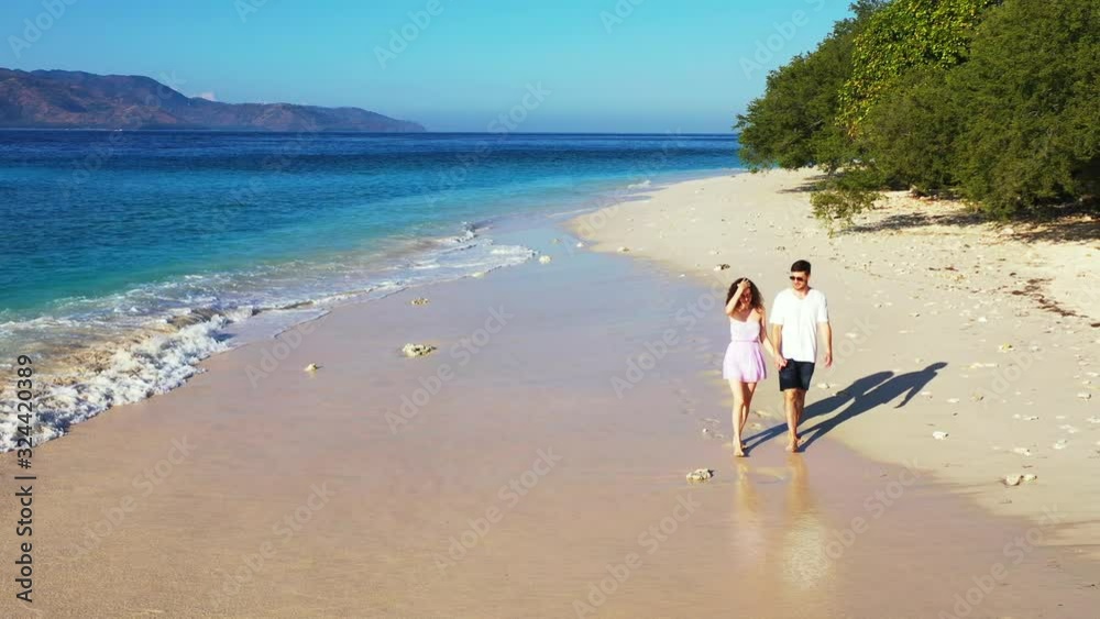Young romantic couple, walking along the seashore of the tropical island beach Young romantic couple, walking along the seashore of the tropical island beach