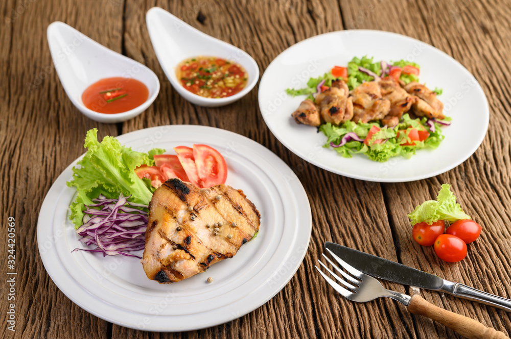 Grilled chicken on a white plate with a salad of tomatoes, carrots and chilies cut into pieces. Grilled chicken on a white plate with a salad of tomatoes, carrots and chilies cut into pieces.