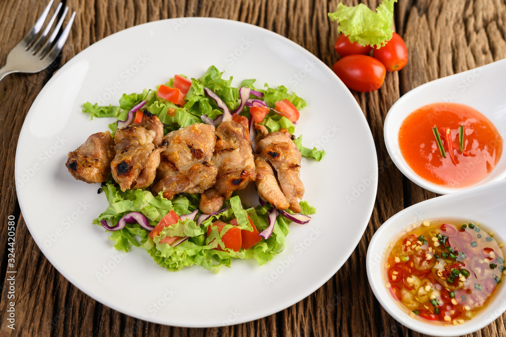 Grilled chicken on a white plate with a salad of tomatoes, carrots and chilies cut into pieces. Grilled chicken on a white plate with a salad of tomatoes, carrots and chilies cut into pieces.