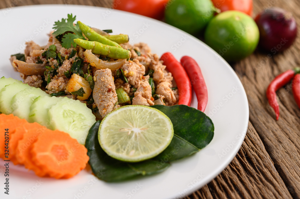 Spicy Minced Pork Salad on a white plate on wooden table. Spicy Minced Pork Salad on a white plate on wooden table.