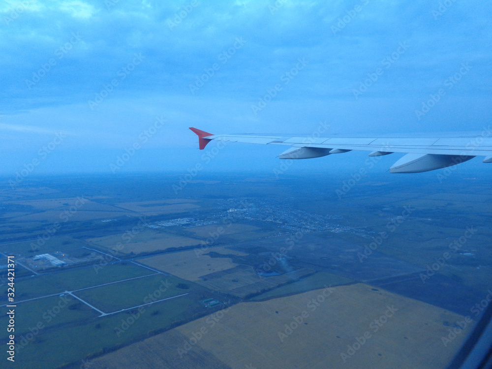 Obraz premium flying in a plane in the sky above the clouds on the wing at dawn aviation vacation