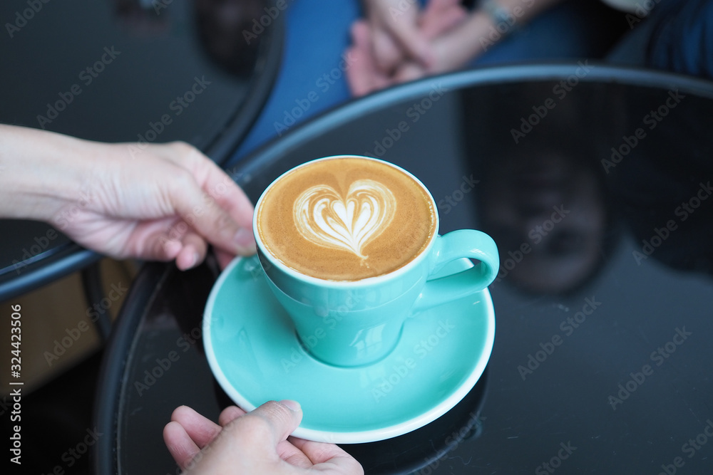 A cup of hot coffee with heart shape latte art on table background. A cup of hot coffee with heart shape latte art on table background.