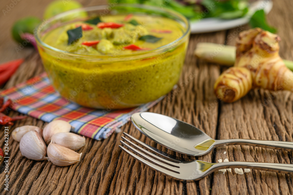 Green curry in a bowl with fork and spoon on wooden table. Green curry in a bowl with fork and spoon on wooden table.