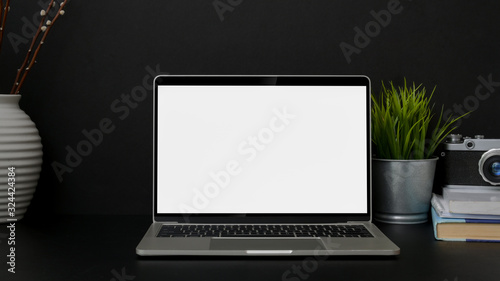 Close up view of trendy designer workplace with blank screen laptop on black table