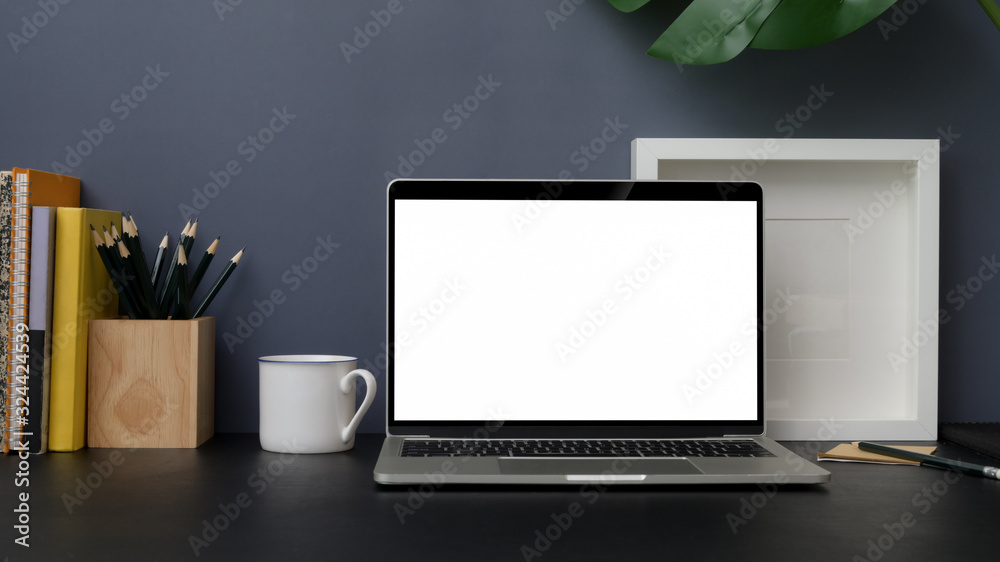 Close up view of trendy workplace with mock up laptop on black table with grey wall Close up view of trendy workplace with mock up laptop on black table with grey wall
