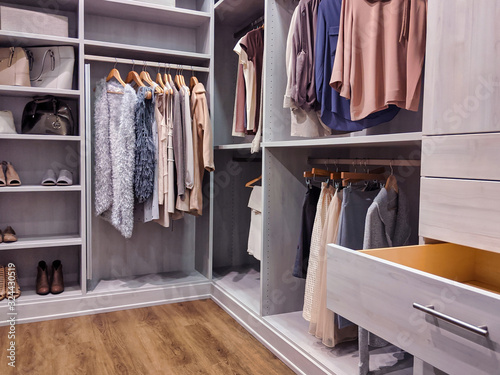 walk in closet with clothes hanging and shoes on shelving photo