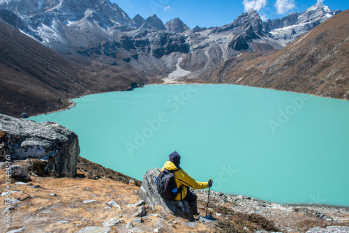 Trekker sitting on the rock and looking to the beautiful view of Gokyo lakes the sacred green lake in Gokyo village one of the most tourist attraction place in Solukhumbu district of Nepal. photo