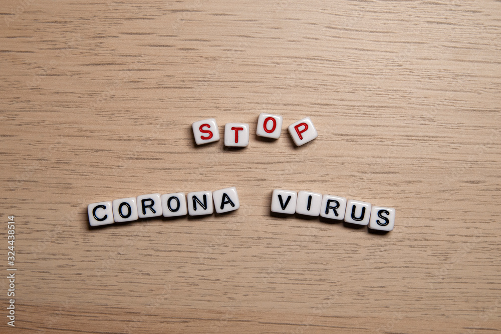 the word STOP CORONA VIRUS in white cubes on a light wooden background. Coronavirus design template
