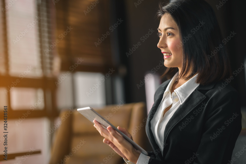 An Asian female executive holding a tablet is enjoying business. An Asian female executive holding a tablet is enjoying business.