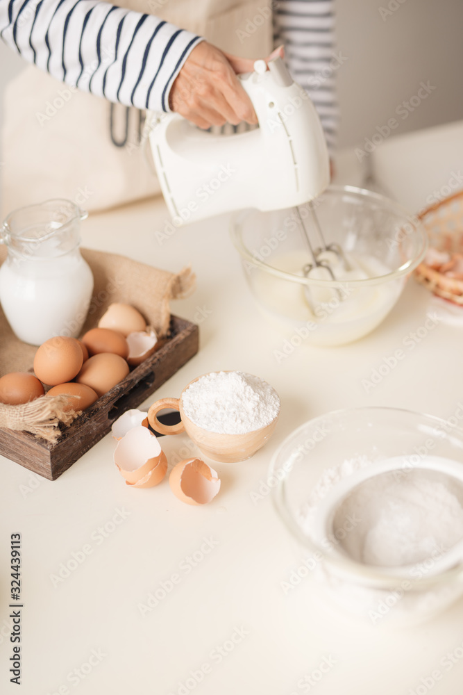 Male hands beating egg whites cream with mixer in the bowl