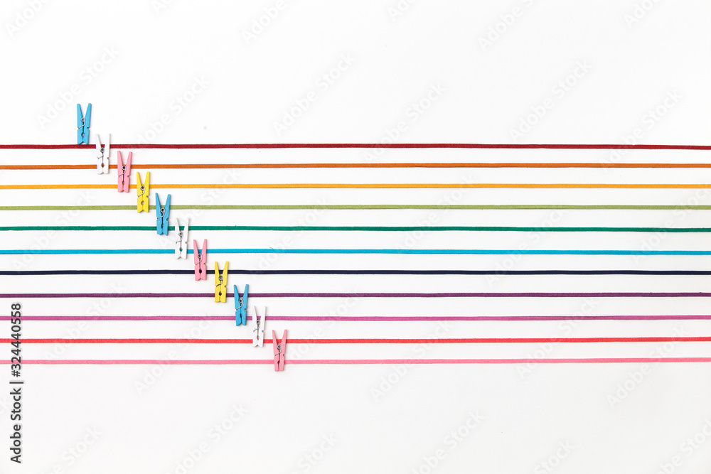 many strands of colorful strings line on white background. 11 eleven straight colorful threads and cloths peg. many strands of colorful strings line on white background. 11 eleven straight colorful threads and cloths peg.