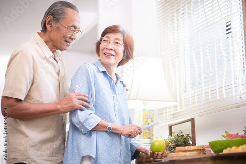 Asian elderly happy couple eating healthy food in the kitchen at home.retirement plan and old people concept