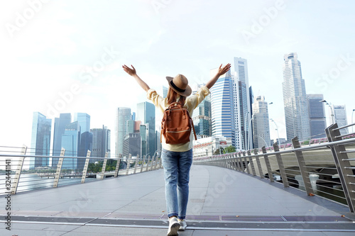 Young woman traveler with backpack and hat traveling into Singapore city downtown. Travelling in Singapore concept. photo