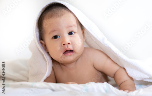Portrait of happy asian smile baby relaxing under towel after bath on the bed