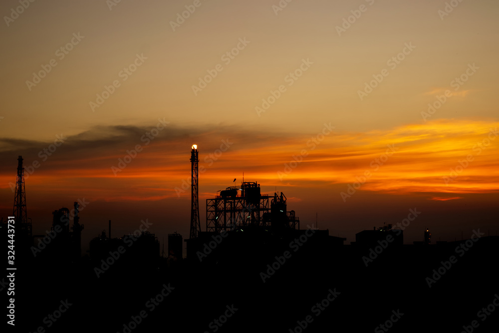 Oil refinery or chemical plant silhouette with night lights on at sunset.