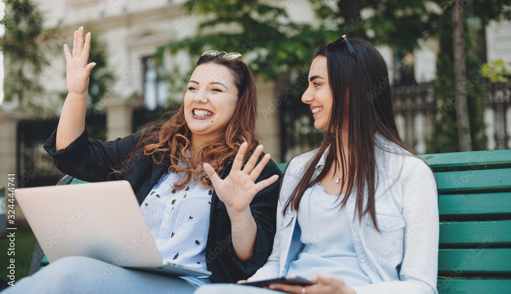 Charming plus sized woman telling future plans to her caucasian sister with black hair and nice smile sitting on a bench in park Charming plus sized woman telling future plans to her caucasian sister with black hair and nice smile sitting on a bench in park