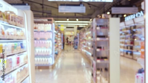 Blurred and trolley slowly moving through cosmetic department within the supermarket.