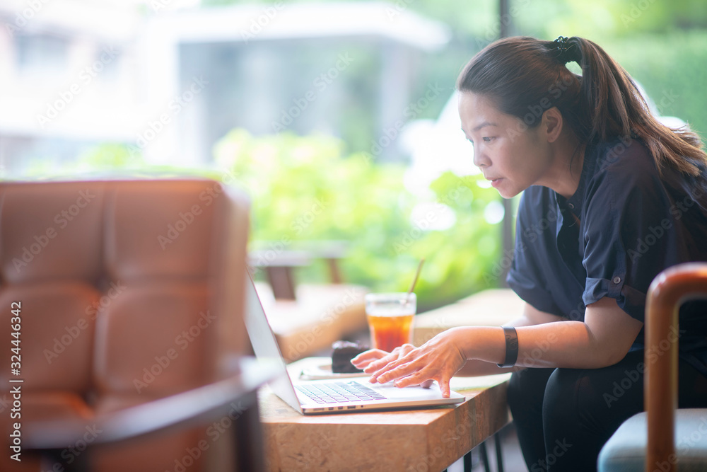 Attractive asian woman smiling, texting and messaging in computer tablet application for online payment or money transfer and looking at notification on smartphone feeling positive in cafe Attractive asian woman smiling, texting and messaging in computer tablet application for online payment or money transfer and looking at notification on smartphone feeling positive in cafe