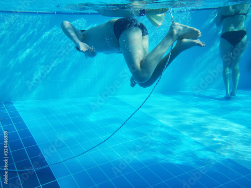 Bodies of boy swimming in a pool under water. Blue