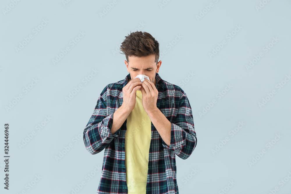 Young man suffering from allergy on light background Young man suffering from allergy on light background