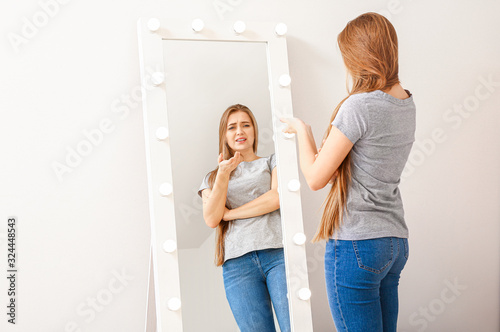 Displeased young woman near mirror at home