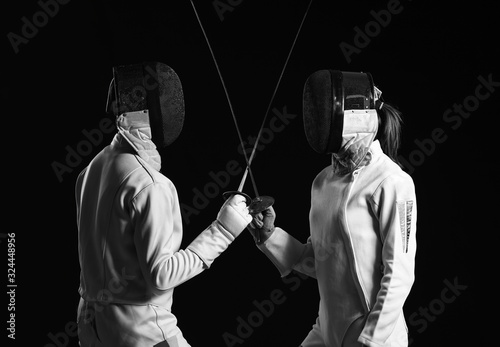 Young fencers on dark background