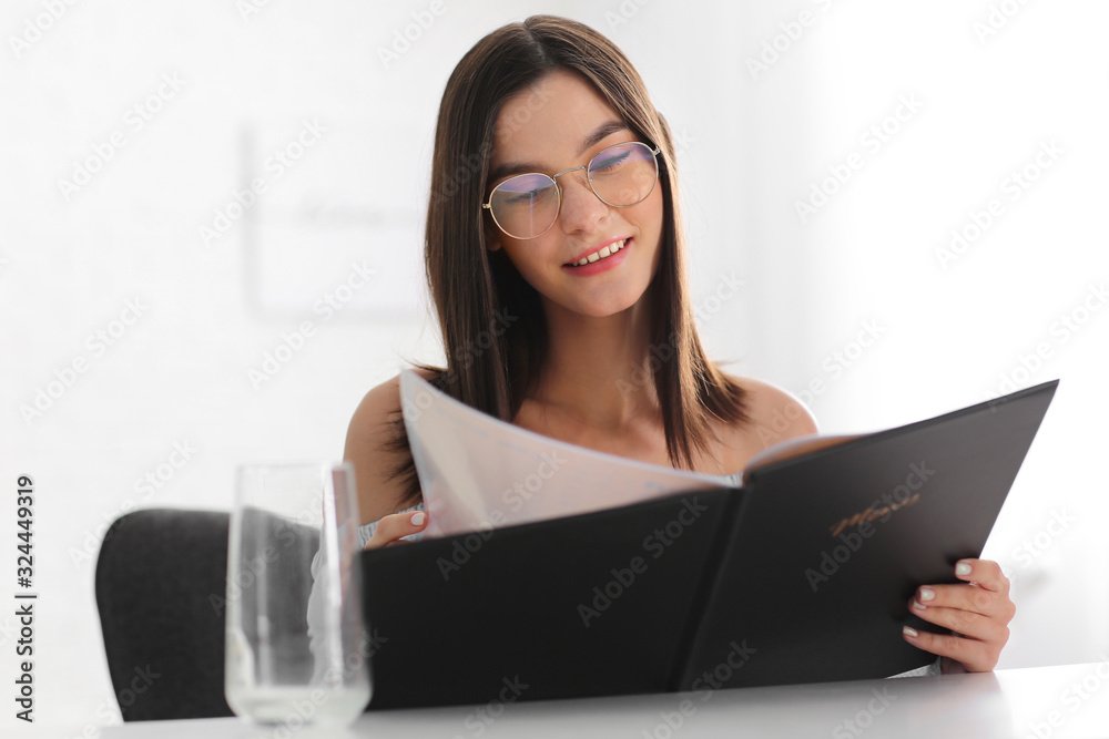 Young woman with menu sitting in restaurant Young woman with menu sitting in restaurant